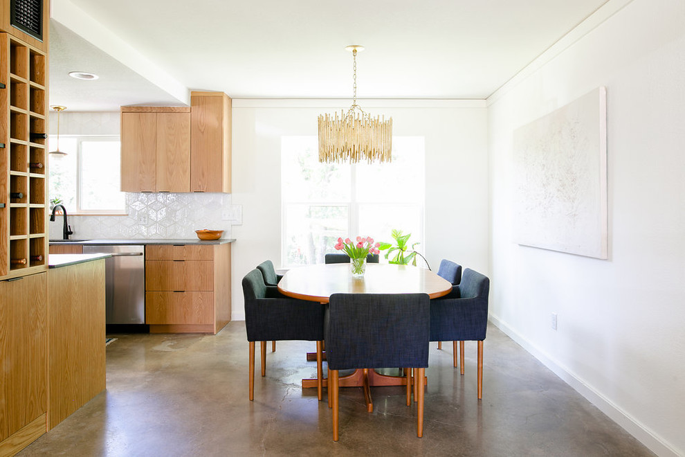 Foto di una sala da pranzo aperta verso il soggiorno minimal con pareti bianche, pavimento in cemento, nessun camino e pavimento grigio