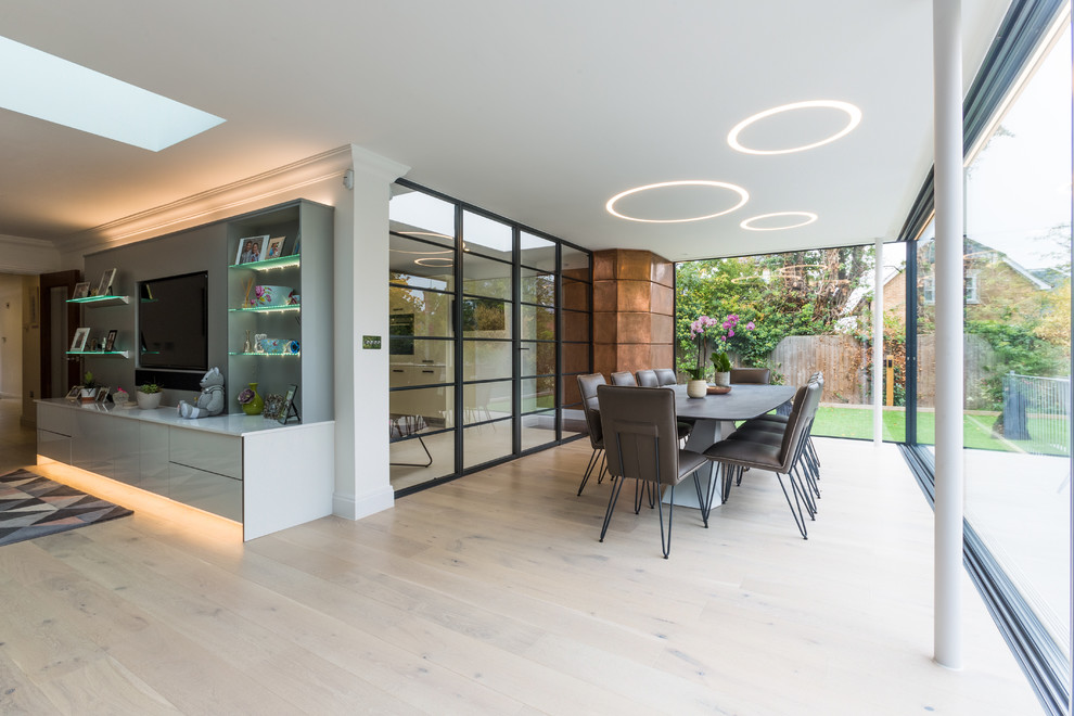 Offenes Modernes Esszimmer mit weißer Wandfarbe, hellem Holzboden und beigem Boden in London