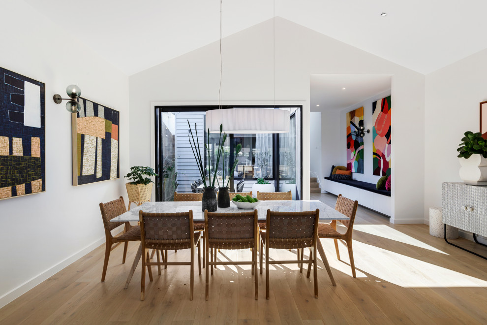 Design ideas for a contemporary open plan dining room in Melbourne with white walls, medium hardwood flooring, no fireplace, brown floors and a vaulted ceiling.