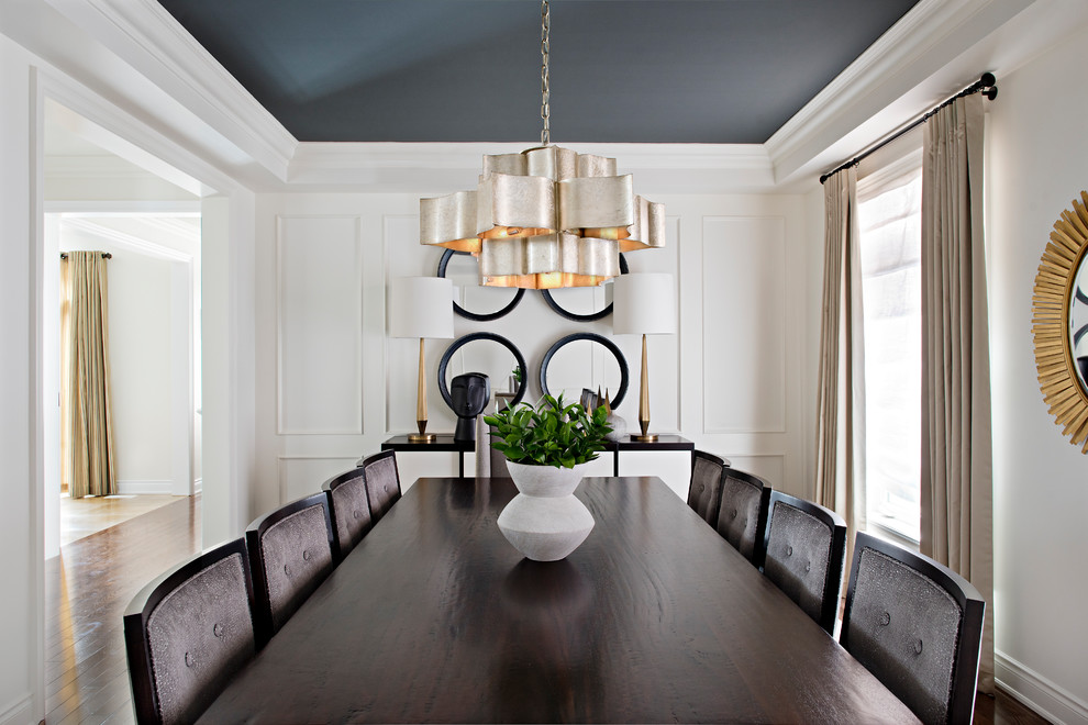 This is an example of a classic enclosed dining room in Toronto with white walls, medium hardwood flooring, brown floors and feature lighting.