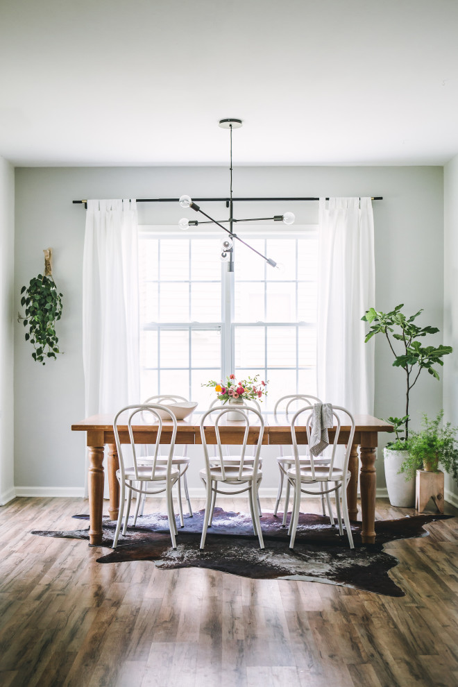 Idée de décoration pour une salle à manger ouverte sur la cuisine nordique de taille moyenne avec un mur gris, sol en stratifié, aucune cheminée et un sol marron.