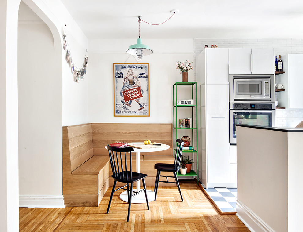 Immagine di una sala da pranzo aperta verso la cucina classica con pareti bianche e parquet chiaro