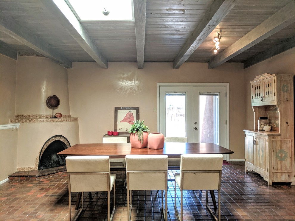 Inspiration pour une salle à manger ouverte sur la cuisine sud-ouest américain de taille moyenne avec un mur beige, tomettes au sol, une cheminée d'angle, un manteau de cheminée en plâtre et un sol marron.