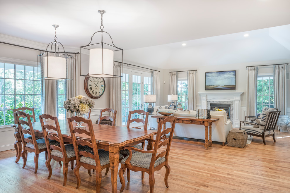 Large classic open plan dining room in Boston with white walls, medium hardwood flooring, a standard fireplace, brown floors and feature lighting.
