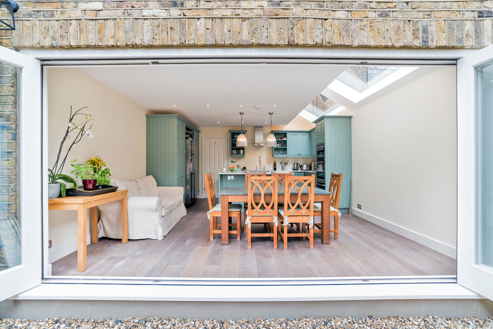 Cette photo montre une salle à manger ouverte sur la cuisine nature avec un mur beige et parquet clair.