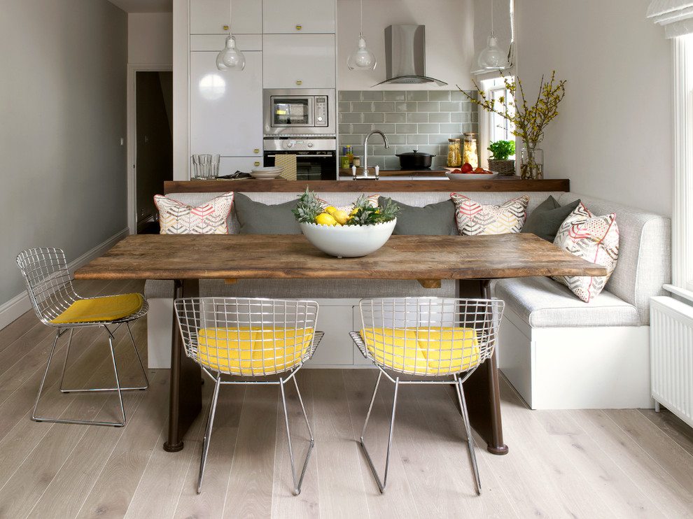 Trendy light wood floor and beige floor kitchen/dining room combo photo in London with white walls