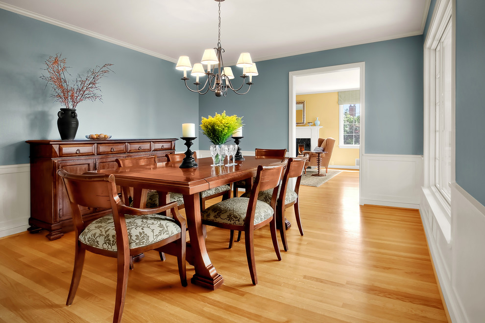Example of a classic medium tone wood floor enclosed dining room design in Seattle with blue walls
