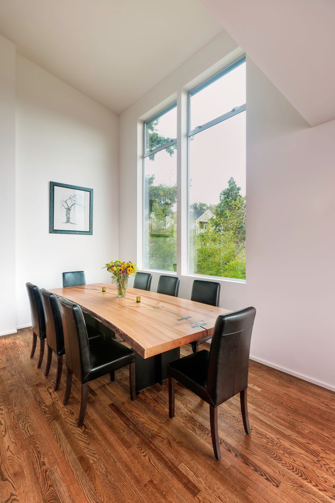 Cette image montre une salle à manger design avec un mur blanc et parquet foncé.