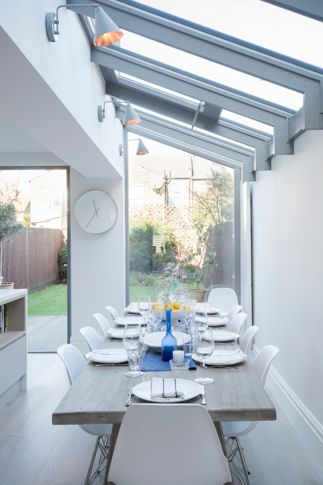 Immagine di una sala da pranzo aperta verso la cucina scandinava di medie dimensioni con pareti bianche e parquet chiaro