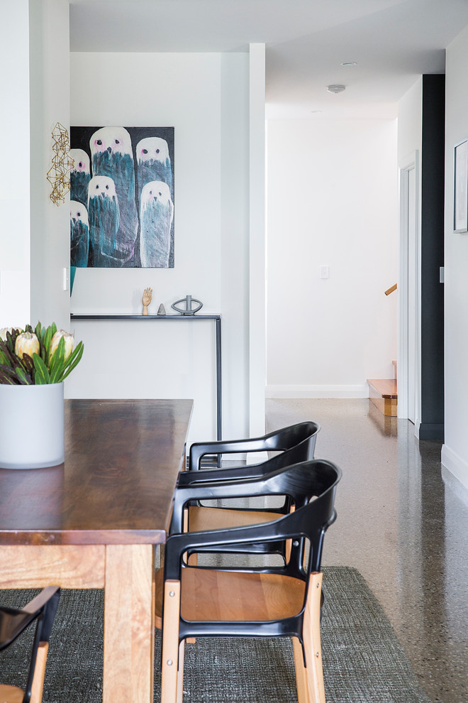 Immagine di una grande sala da pranzo aperta verso la cucina design con pareti bianche e pavimento in cemento