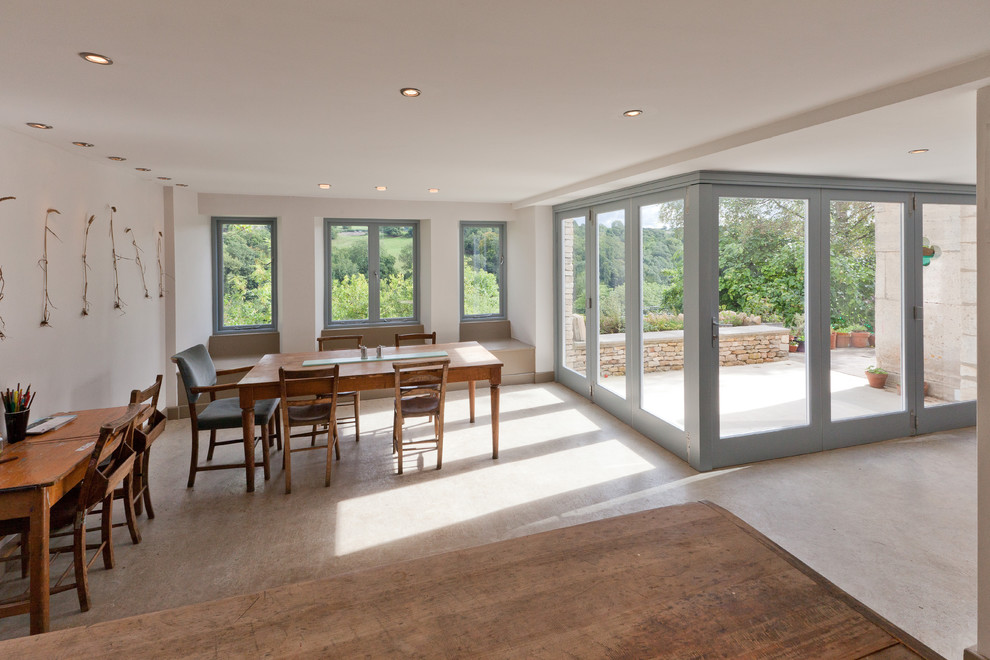 Photo of a country kitchen/dining room in Gloucestershire with white walls and concrete flooring.