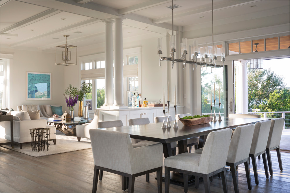 Foto di una sala da pranzo aperta verso il soggiorno costiera con pareti bianche, parquet scuro e pavimento marrone