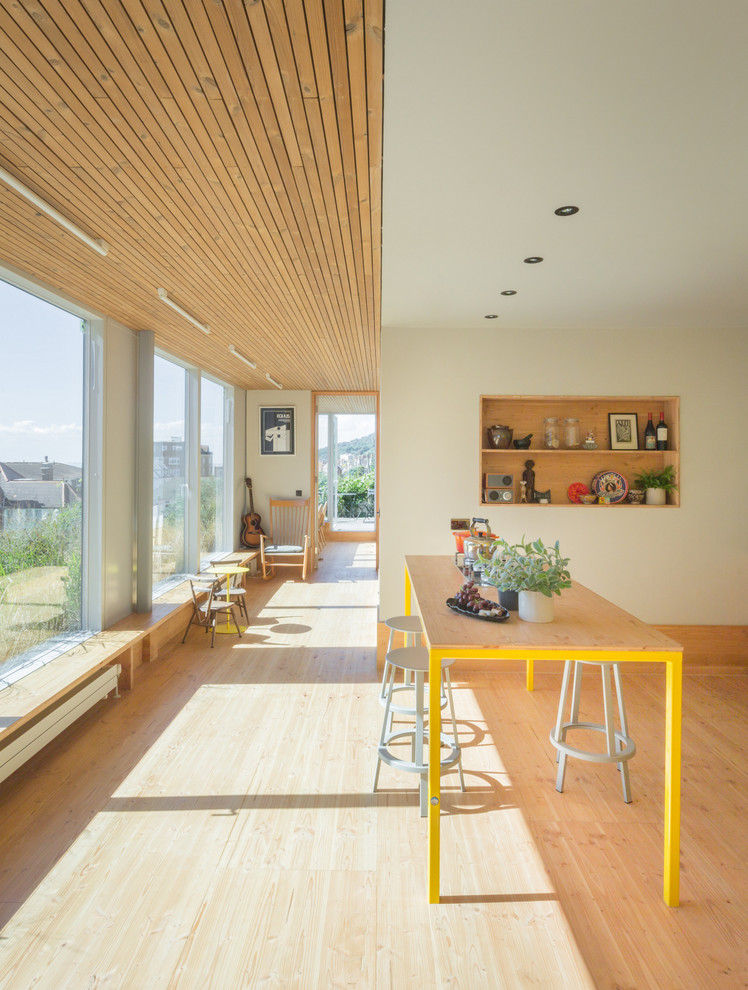 Foto di una grande sala da pranzo aperta verso la cucina contemporanea con pareti beige, parquet chiaro e pavimento beige