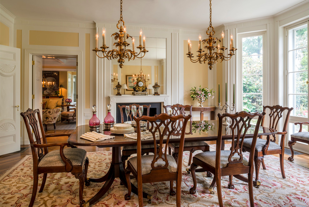 Example of a large classic medium tone wood floor enclosed dining room design in Philadelphia with yellow walls and a standard fireplace