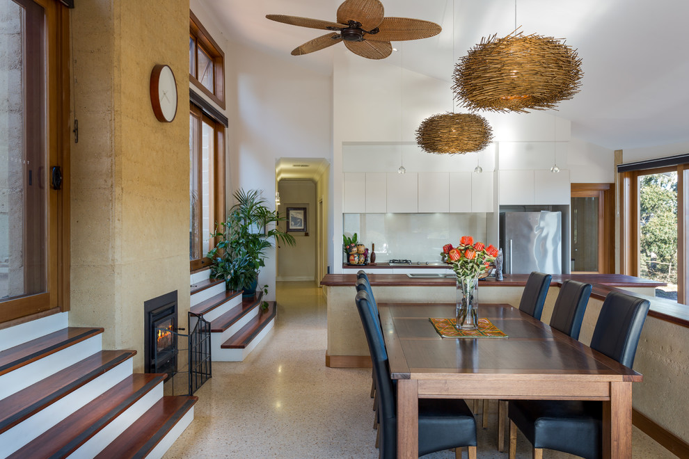 Réalisation d'une grande salle à manger ouverte sur la cuisine design avec un mur blanc, une cheminée standard et sol en béton ciré.