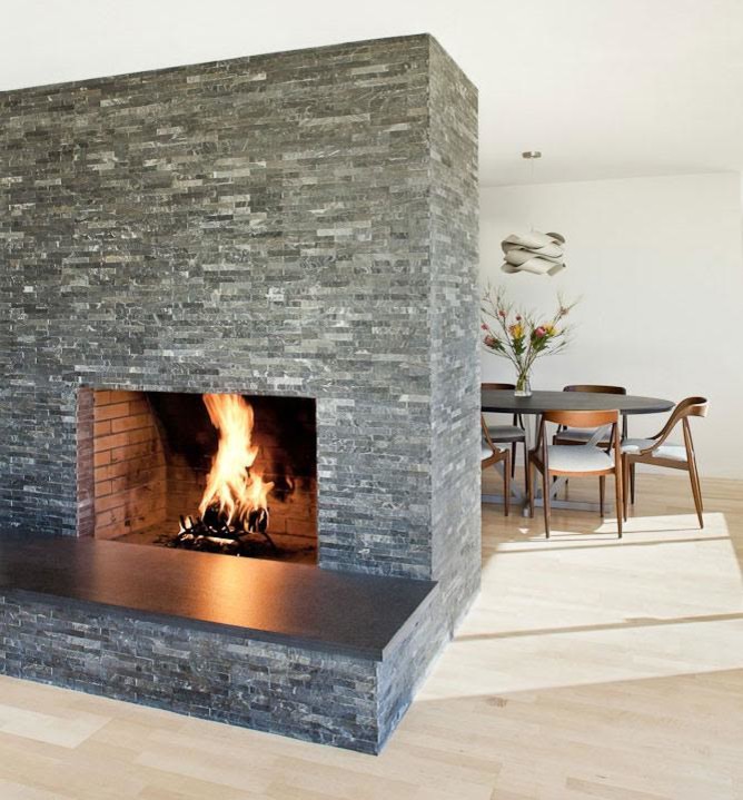 This is an example of a modern dining room in San Francisco with a stone fireplace surround, white walls, light hardwood flooring and a ribbon fireplace.