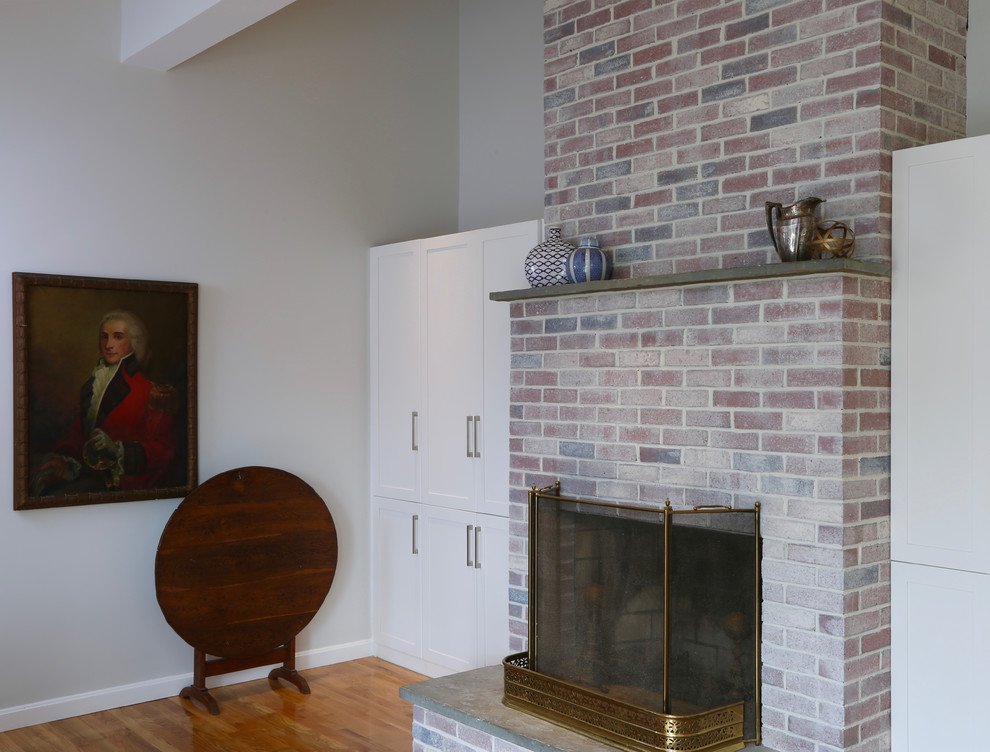 Réalisation d'une salle à manger ouverte sur la cuisine tradition de taille moyenne avec un mur blanc, un sol en bois brun, une cheminée standard et un manteau de cheminée en brique.