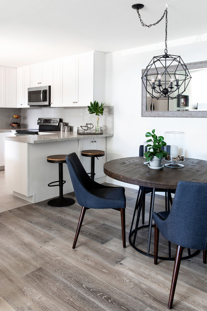 This is an example of a small modern kitchen/dining room in San Diego with white walls, laminate floors and grey floors.