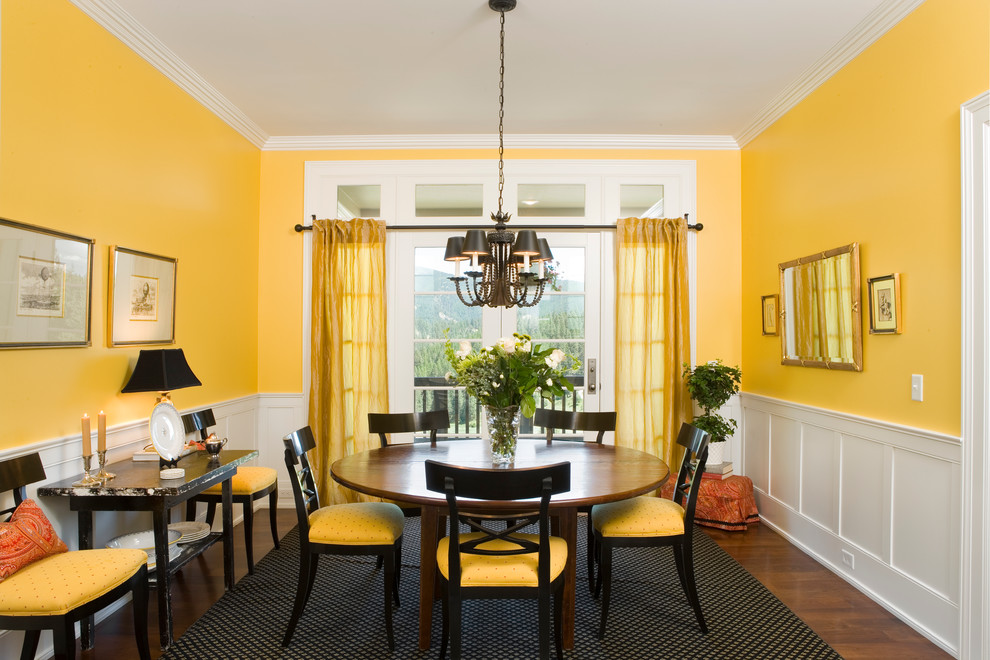 Immagine di una sala da pranzo classica chiusa e di medie dimensioni con pareti gialle, parquet scuro e nessun camino
