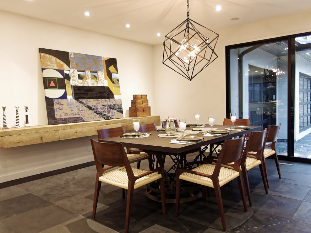 Idée de décoration pour une salle à manger ouverte sur le salon design de taille moyenne avec un mur blanc et un sol en ardoise.