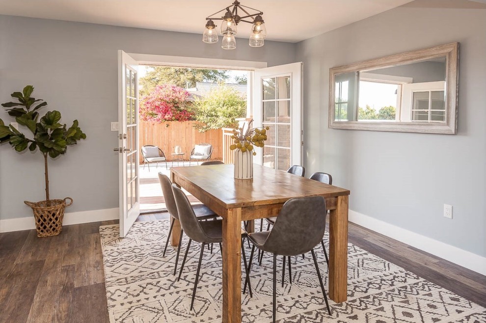 Aménagement d'une petite salle à manger ouverte sur le salon craftsman avec un mur bleu, parquet foncé et un sol marron.