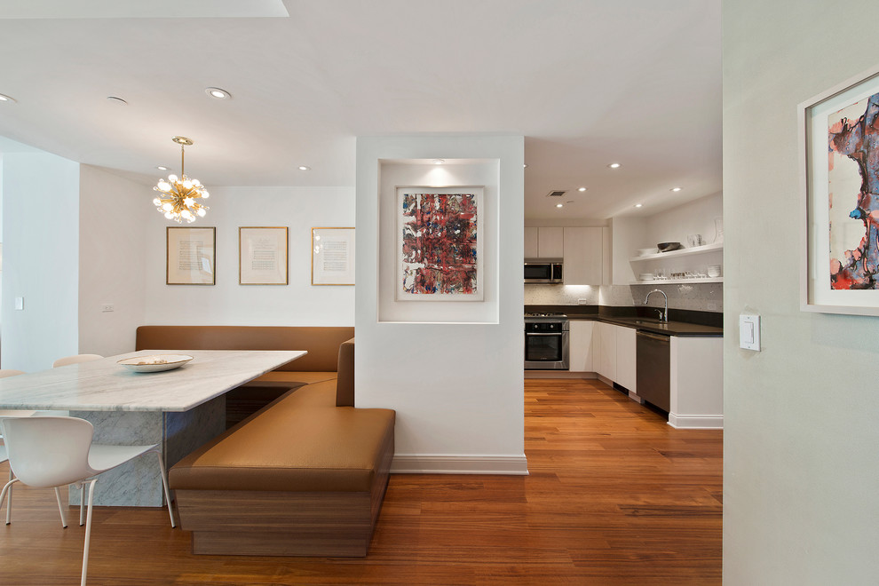 Idée de décoration pour une salle à manger ouverte sur le salon design avec un mur blanc et un sol en bois brun.