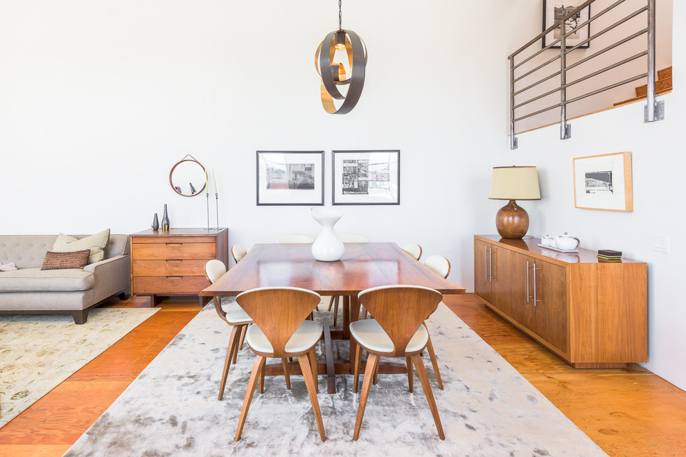 Foto di una sala da pranzo aperta verso il soggiorno minimalista con pareti bianche e pavimento in legno massello medio