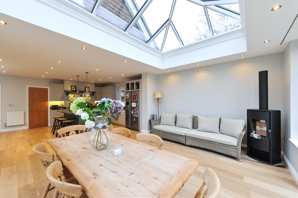 Offenes, Mittelgroßes Landhaus Esszimmer mit beiger Wandfarbe, hellem Holzboden und Kaminofen in Surrey