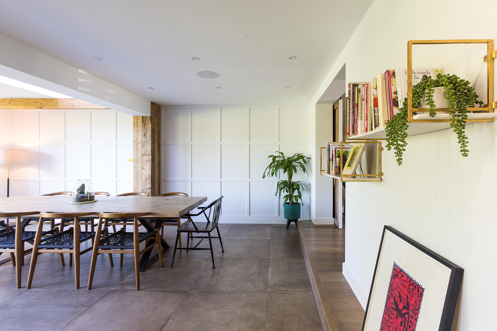 Cette image montre une grande salle à manger ouverte sur le salon design avec un mur blanc, un sol en carrelage de céramique et un sol marron.