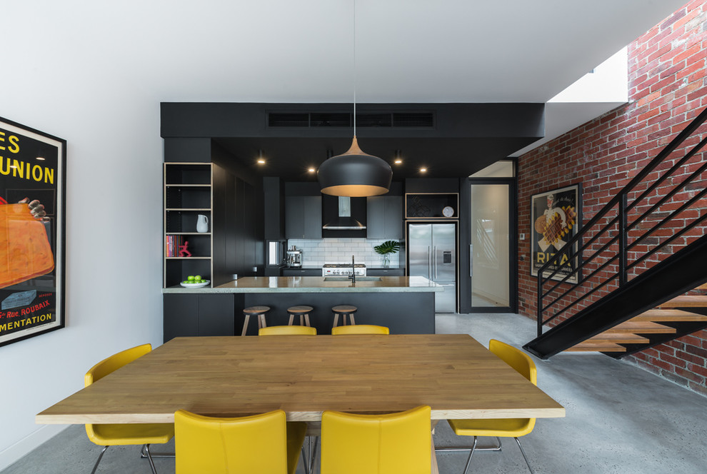 Immagine di una sala da pranzo aperta verso il soggiorno industriale di medie dimensioni con pareti bianche e pavimento in cemento