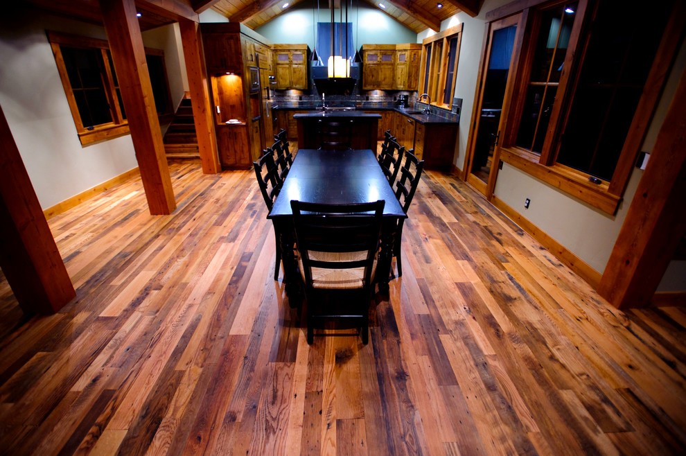 Cette image montre une grande salle à manger ouverte sur le salon traditionnelle avec un mur blanc, un sol en bois brun et aucune cheminée.