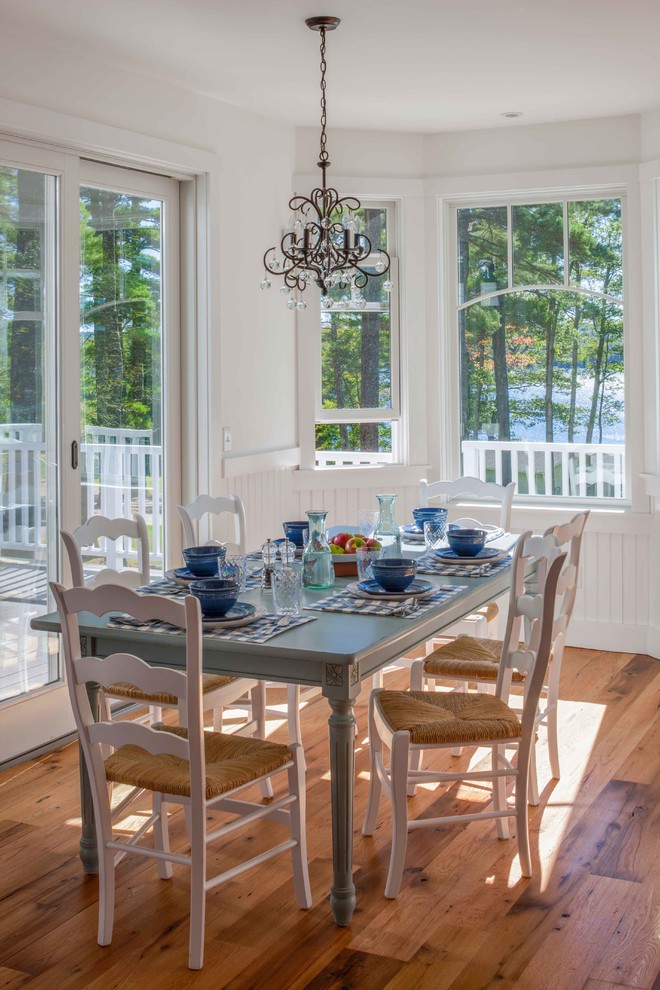 Exemple d'une salle à manger ouverte sur la cuisine chic avec un mur blanc et un sol en bois brun.
