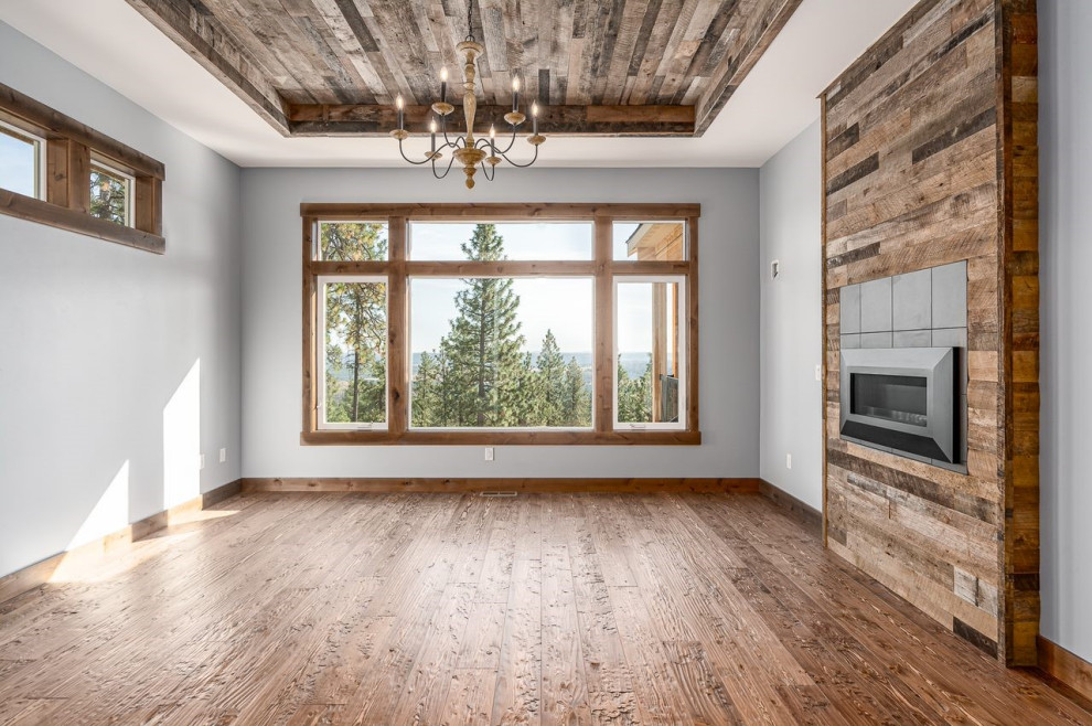 Exemple d'une salle à manger montagne en bois fermée avec un mur gris, un sol en bois brun, cheminée suspendue, un manteau de cheminée en bois, un sol marron et un plafond en bois.