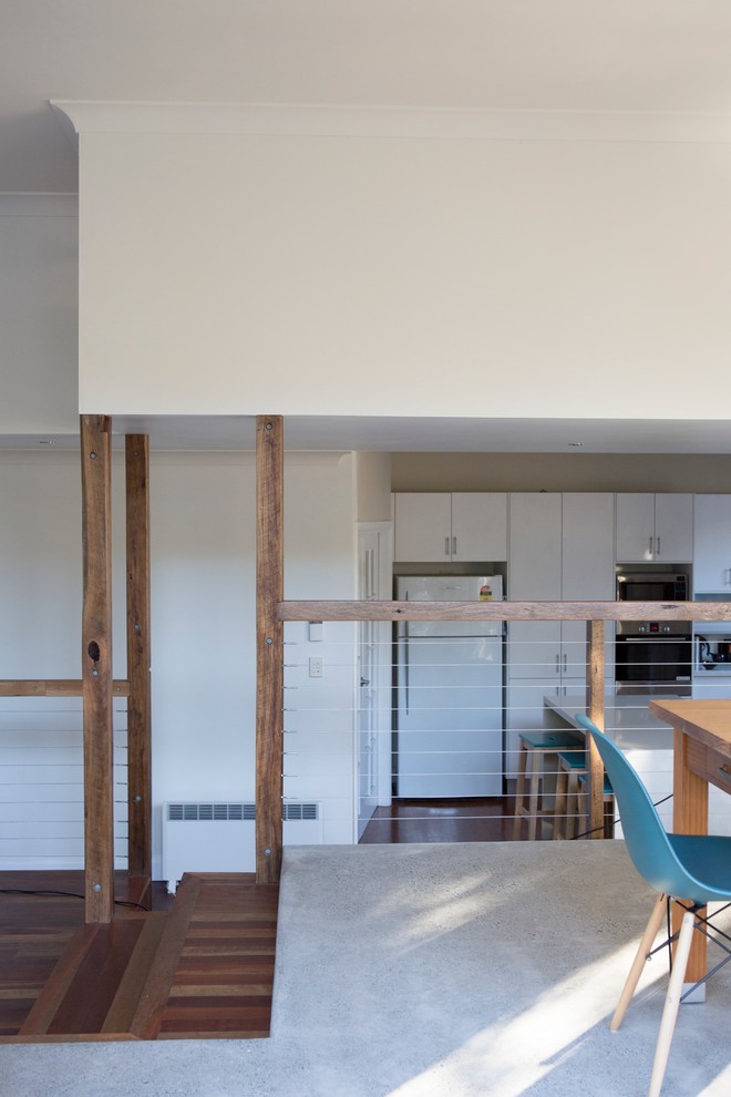 Foto di una sala da pranzo aperta verso il soggiorno minimal di medie dimensioni con pareti bianche e pavimento in cemento