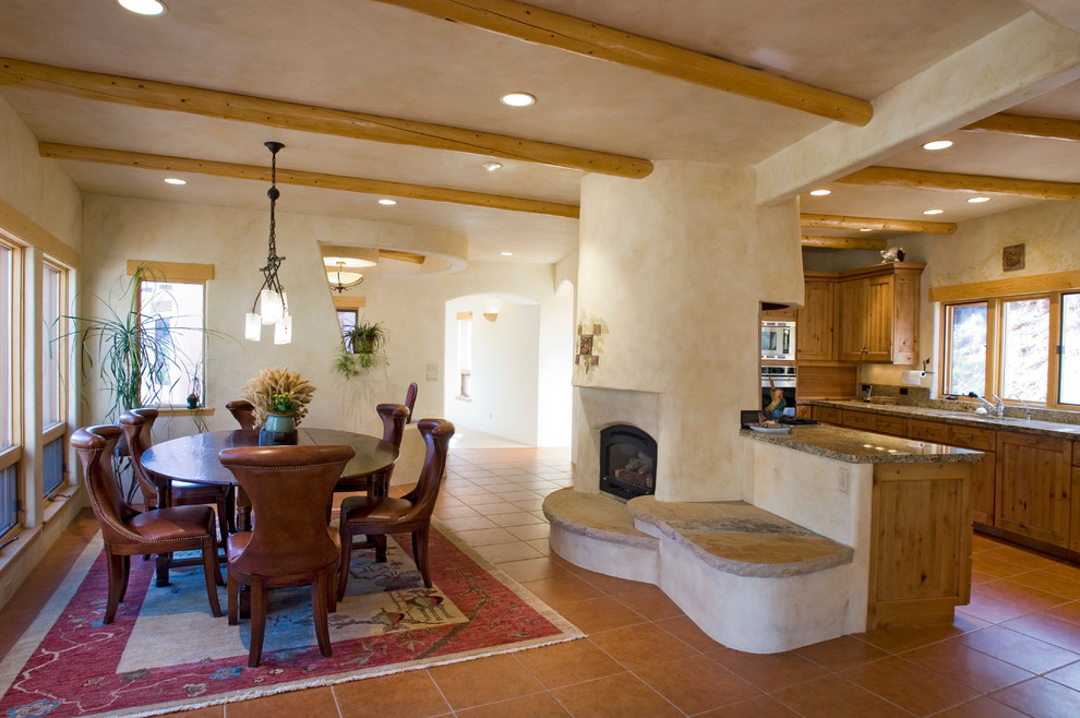 На фото: кухня-столовая среднего размера с бежевыми стенами, полом из терракотовой плитки и стандартным камином с