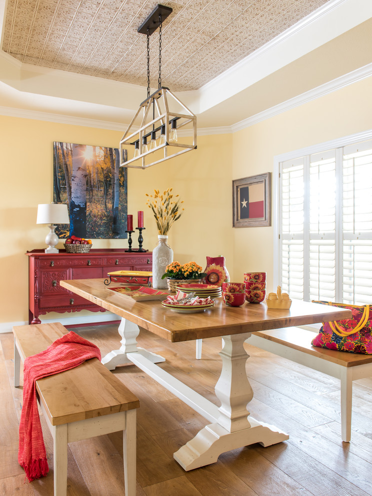 Design ideas for a country dining room in Austin with yellow walls, medium hardwood flooring and feature lighting.