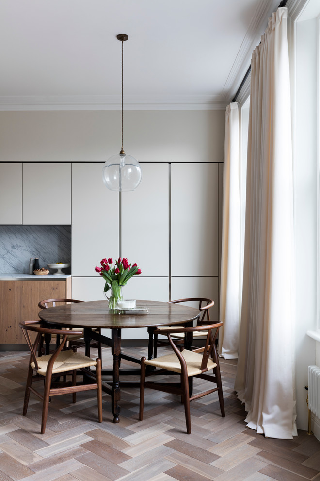 This is an example of a scandinavian dining room in London with beige walls and dark hardwood flooring.