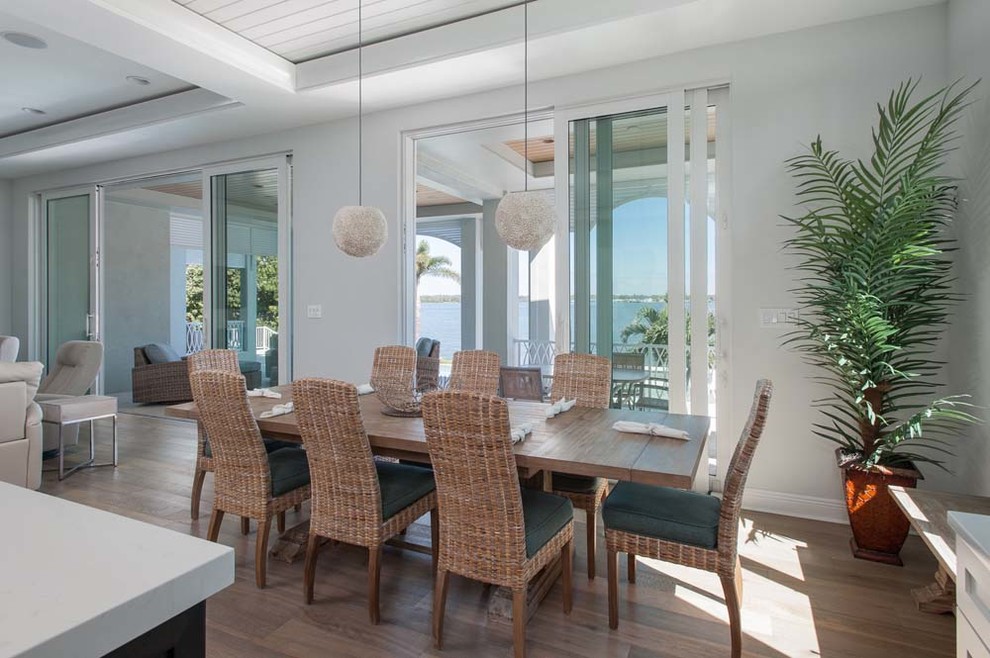 Aménagement d'une salle à manger ouverte sur le salon bord de mer de taille moyenne avec un mur blanc, un sol en bois brun, aucune cheminée et un sol marron.