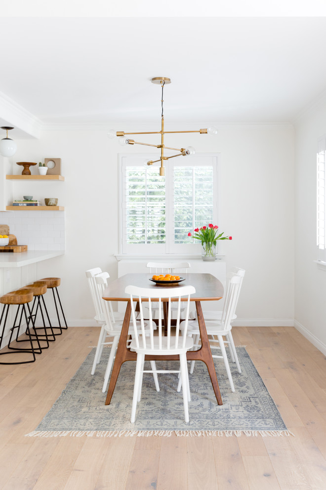 Foto di una sala da pranzo aperta verso la cucina stile marinaro con pareti bianche, parquet chiaro, nessun camino e pavimento beige