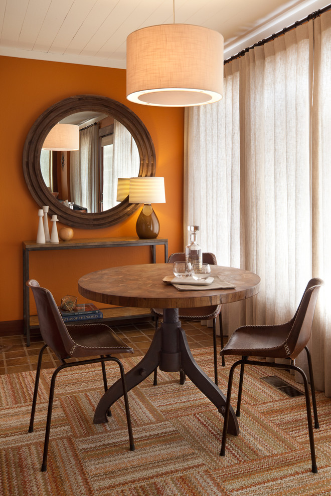 Cette image montre une petite salle à manger ouverte sur le salon bohème avec un mur orange, un sol en carrelage de porcelaine, un sol marron, aucune cheminée et éclairage.