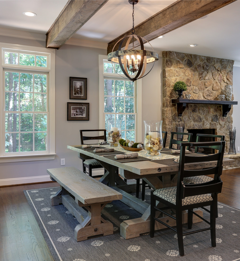 Aménagement d'une grande salle à manger ouverte sur le salon montagne avec un mur gris, parquet foncé, une cheminée standard, un manteau de cheminée en pierre et un sol marron.