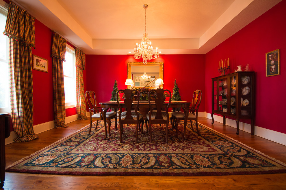 Immagine di una grande sala da pranzo aperta verso il soggiorno tradizionale con pareti rosse e parquet chiaro