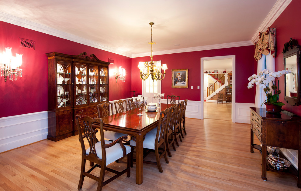 Diseño de comedor clásico grande abierto sin chimenea con paredes rojas y suelo de madera clara