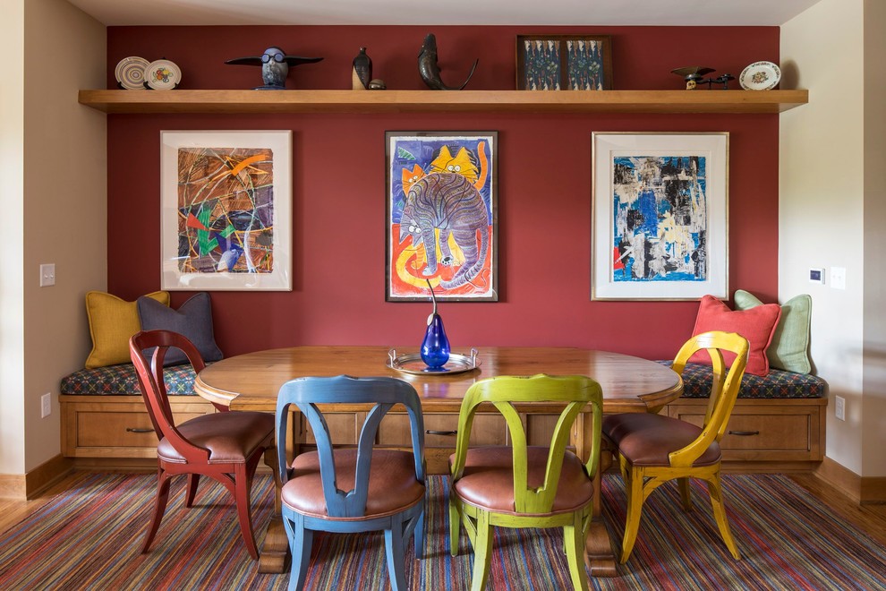 Cette image montre une salle à manger bohème avec un mur rouge, un sol en bois brun et un sol marron.