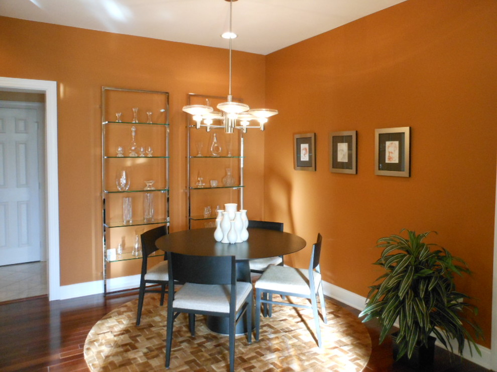 Immagine di una sala da pranzo minimal chiusa e di medie dimensioni con pareti arancioni e parquet scuro