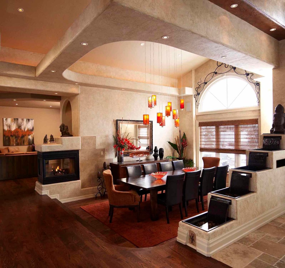 Aménagement d'une salle à manger éclectique fermée et de taille moyenne avec un mur beige, parquet foncé, une cheminée double-face et un manteau de cheminée en métal.