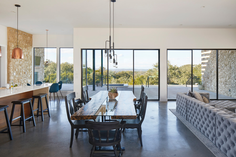 Идея дизайна: большая кухня-столовая в стиле модернизм с бежевыми стенами, бетонным полом, стандартным камином, фасадом камина из камня и серым полом