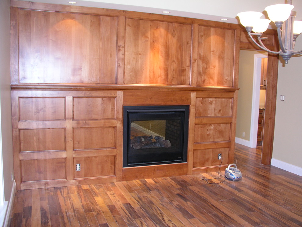 Cette photo montre une salle à manger chic avec un sol en bois brun, une cheminée double-face, un manteau de cheminée en bois et un sol marron.