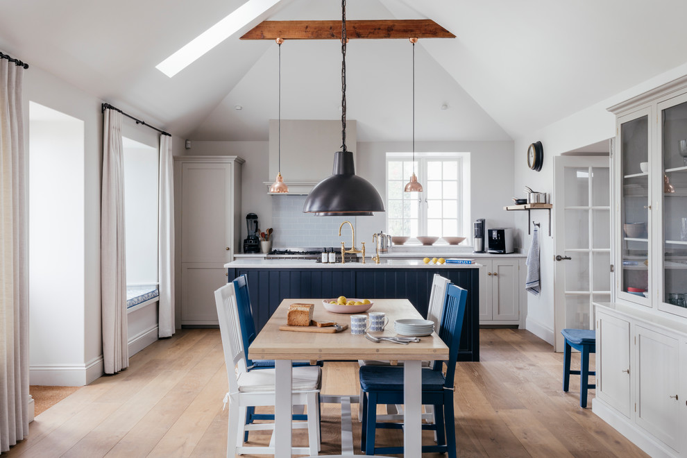 Medium sized coastal open plan dining room in Cornwall with medium hardwood flooring, brown floors and white walls.