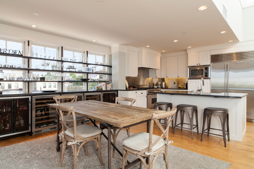 Exemple d'une salle à manger ouverte sur la cuisine chic de taille moyenne avec un sol en bois brun et un mur gris.